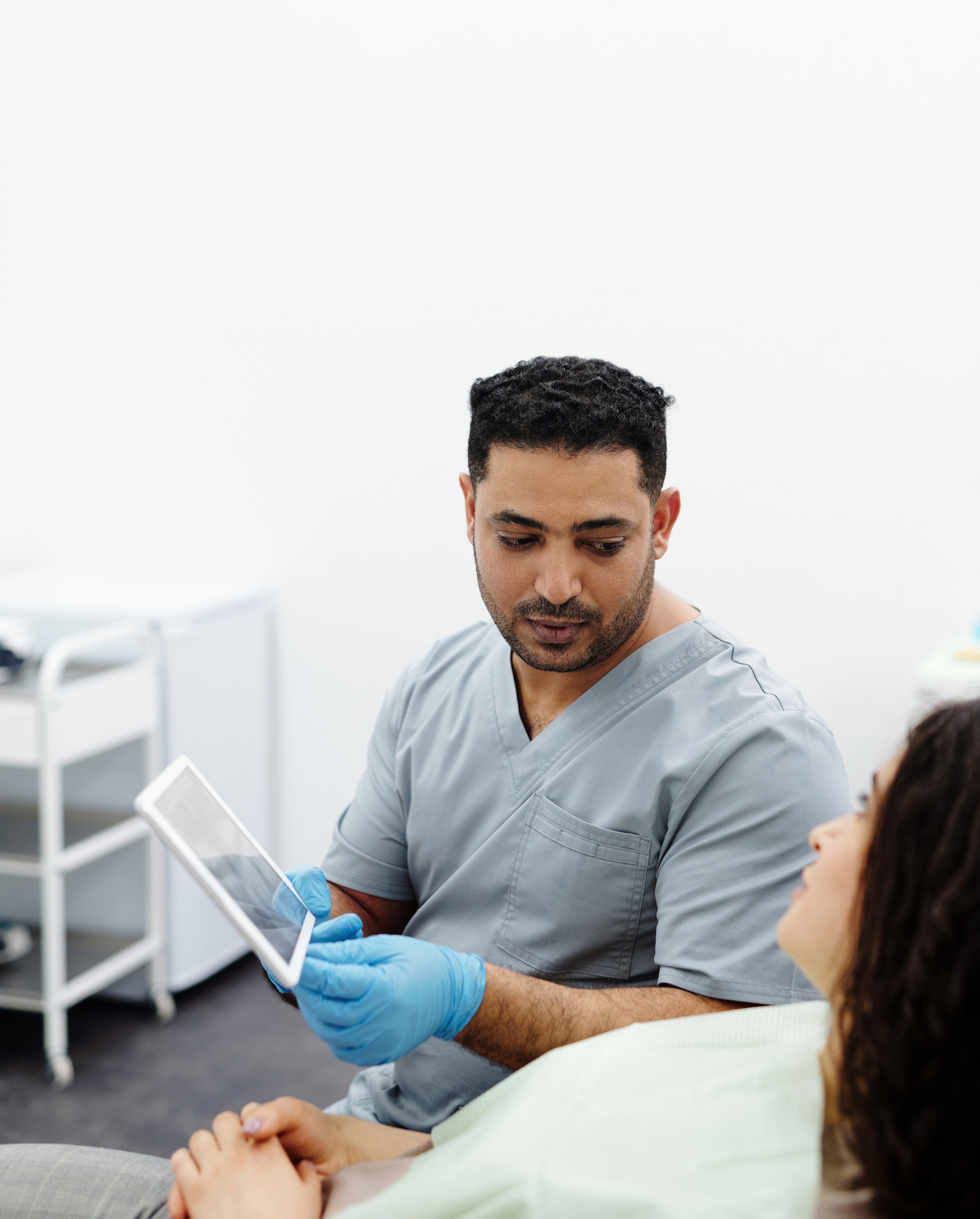 Male nurse wearing scrubs showing a tablet screen to female patient