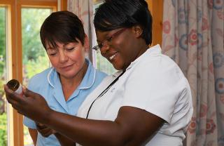 Two nurses looking at information on a bottle