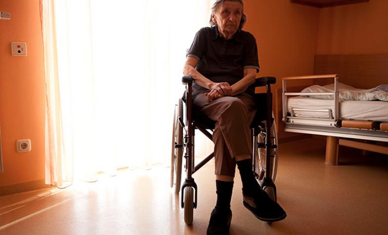 Stock photo of women in wheelchair facing away from a window that has sunlight streaming through