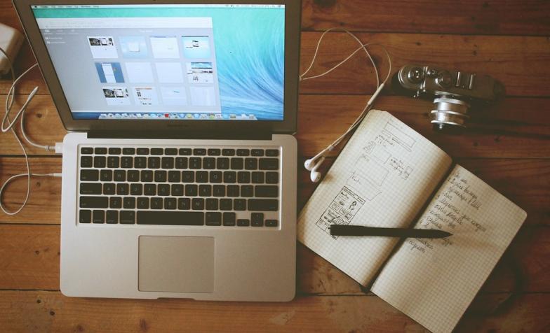 Desk with laptop, notebook and headphones