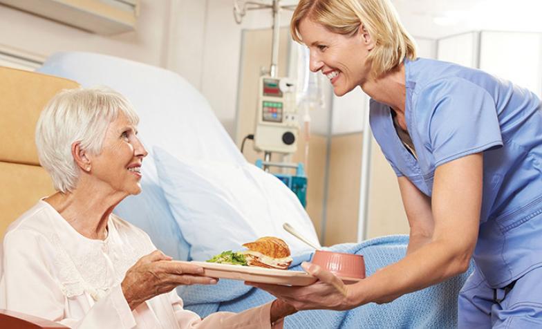 A stock photo of a nurse providing food to a patient