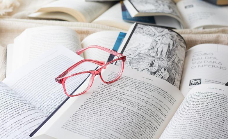 A stock image of a pair of glasses resting on a number of books