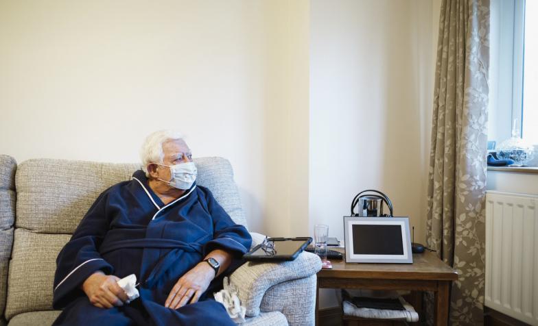 Man with mask on looking out of window