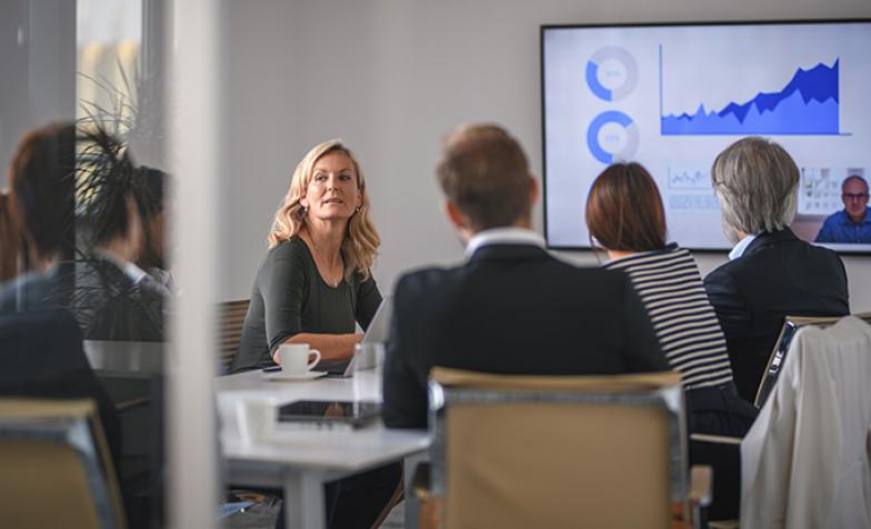 Stock photo of a group of men and women, seated, having a board meeting