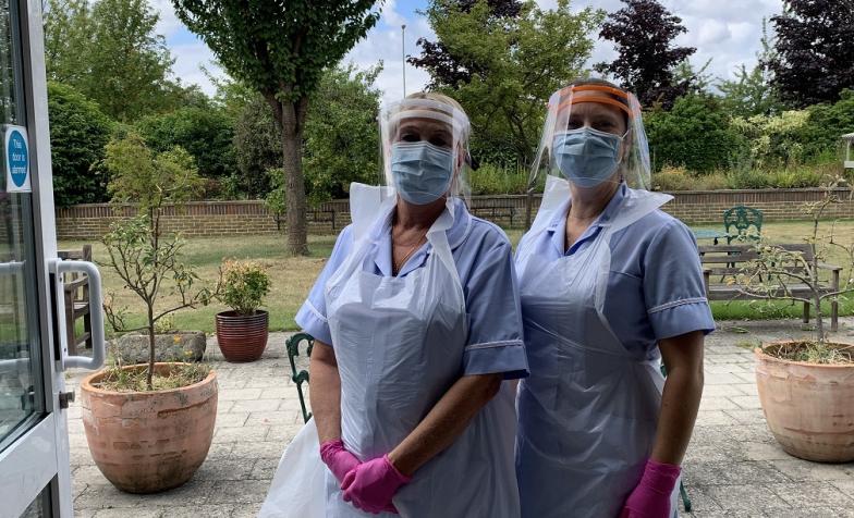 Two nurses in full PPE outside a building
