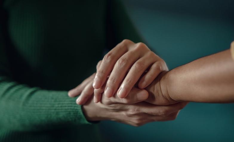 Stock photo of two people holding hands supportively