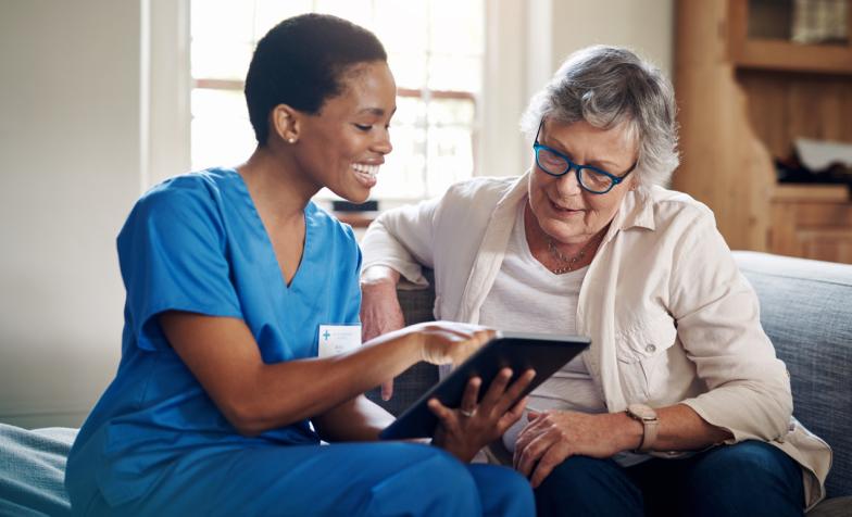 Carer with iPad and older woman