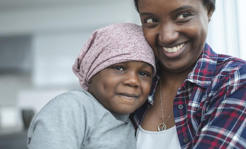 A mother hugs her daughter who is wearing a bandana