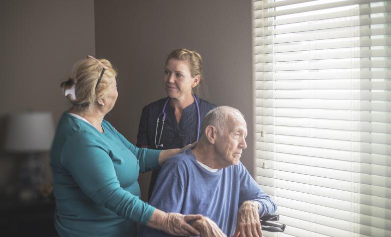 Man in hospice looking out the window surrounded by hospice staff
