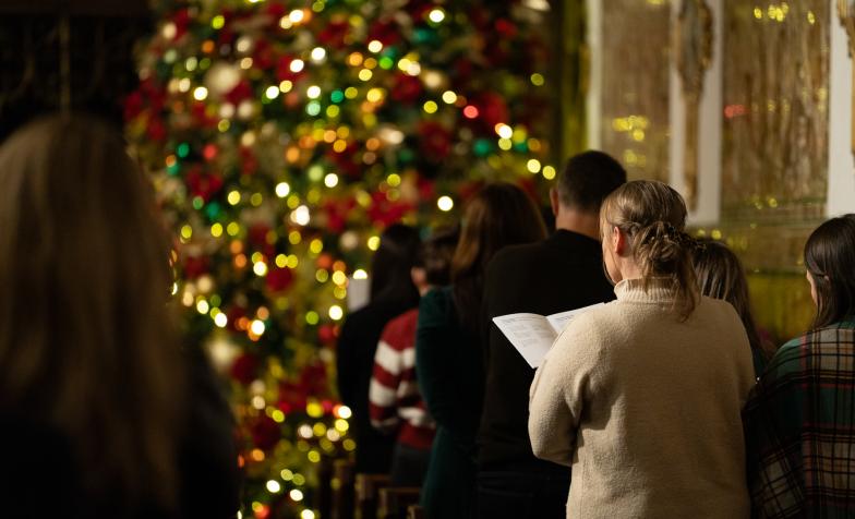 Woman singing carols by christmas tree