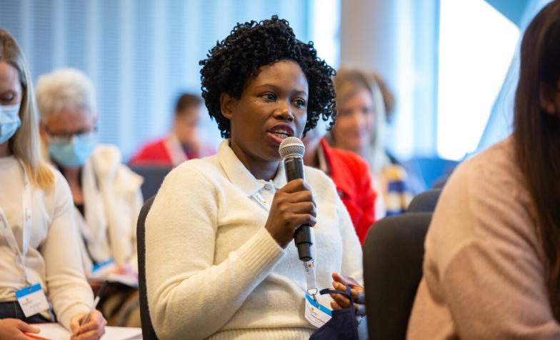 A woman with short black hair asking a question into a microphone.