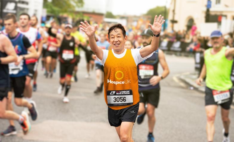 Runner in Hospice UK vest smiles and waves 