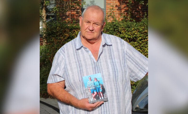 A man wearing a shirt and holding up a book
