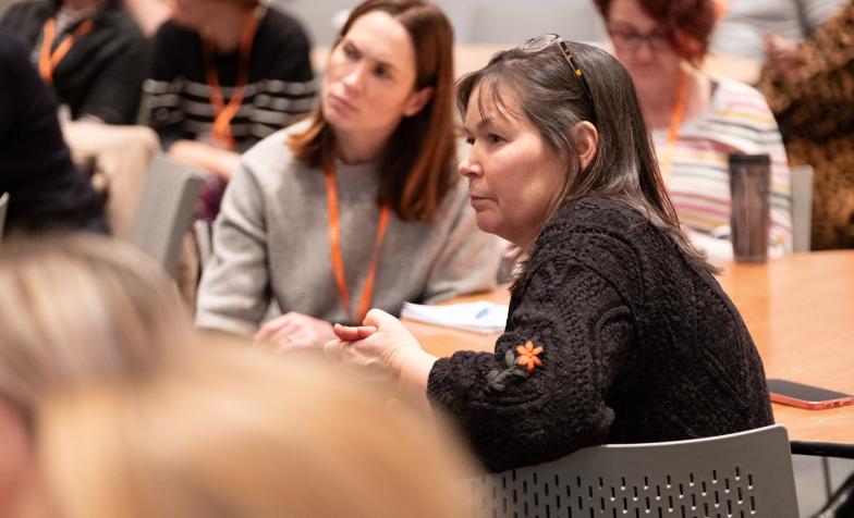 Two women seated at a table taking part in a conference session