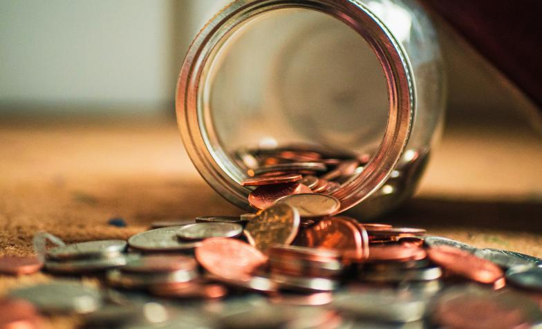 A stock photograph from Unsplash showng a jar tipped over, that had been filled with money