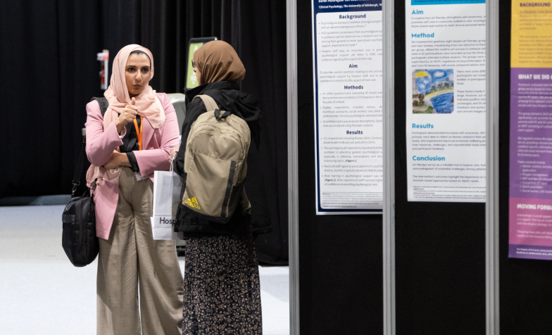 Two women having a conversation next to the poster exhibition at National Conference