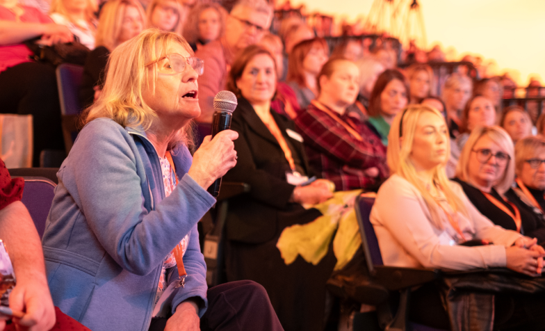 A woman in the audience at National Conference asking a question into a microphone