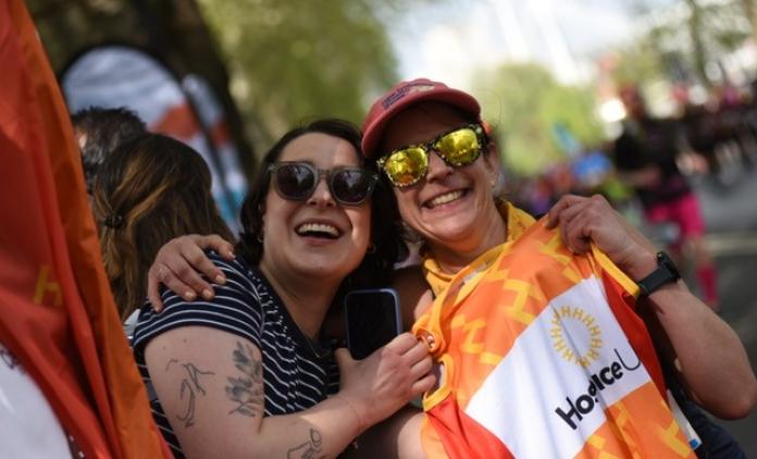 Two smiling supporters, holding up a Hospice UK running vest and embracing