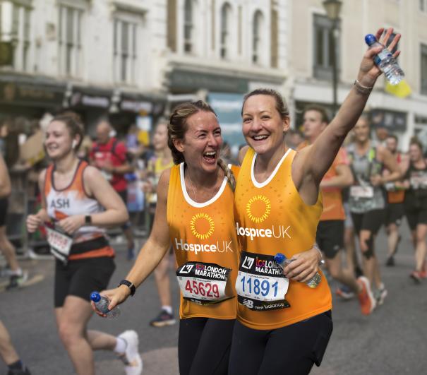 London Marathon 2025 - Two runners hugging and smiling wearing Hospice UK running vests