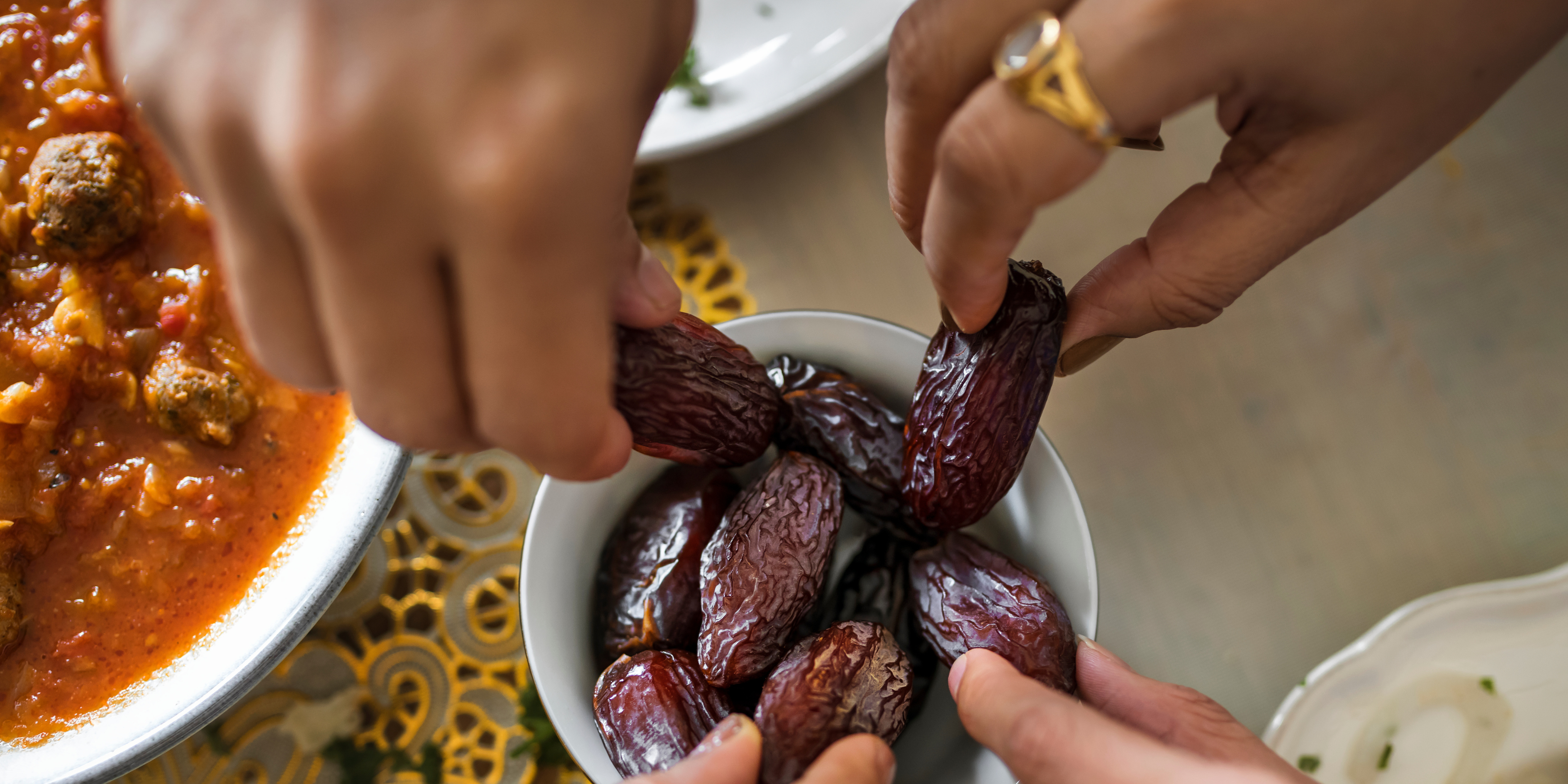 Multiple people sharing a meal and picking up dates with their hands