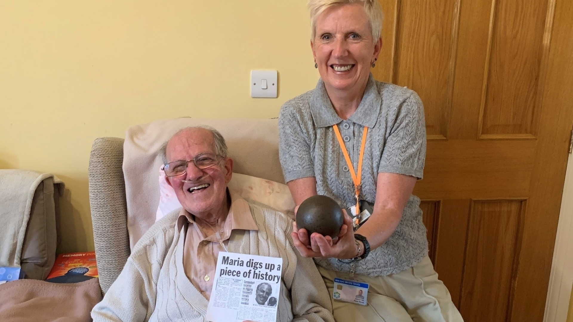 An elderly man and woman holding a cannonball