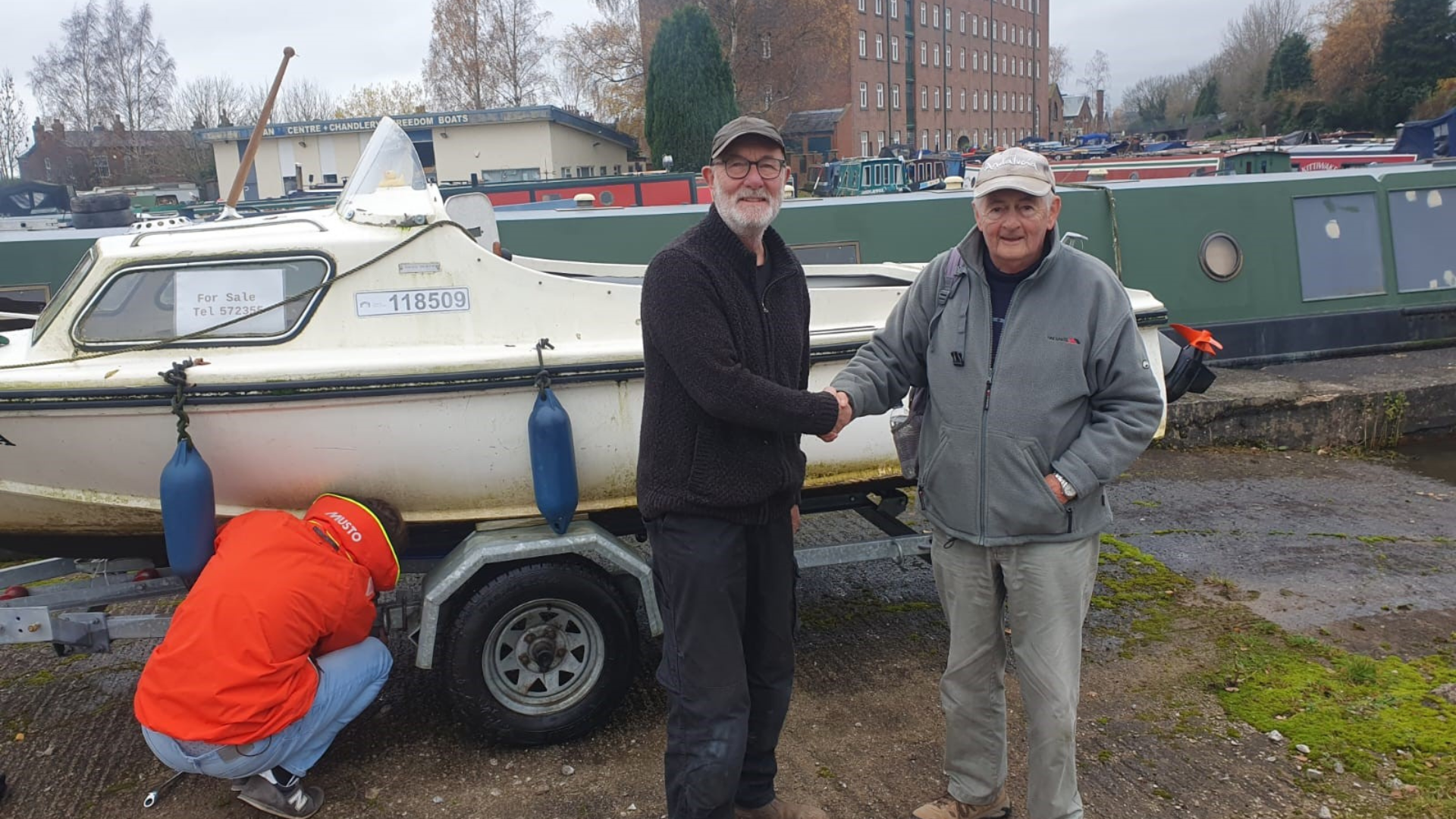 Two men shaking hands in front of a boat