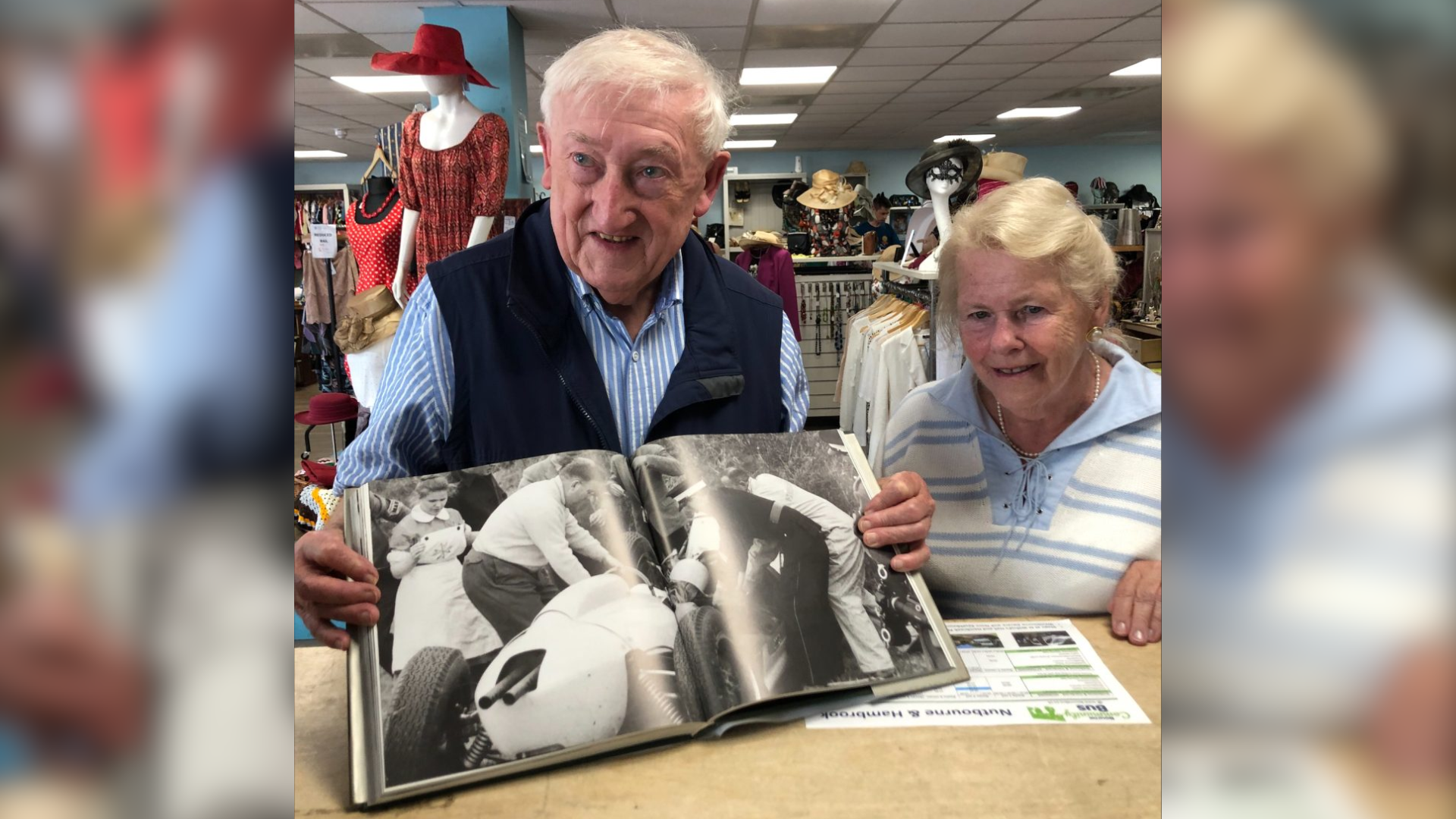 An elderly man and woman holding up an open book showing a photo inside