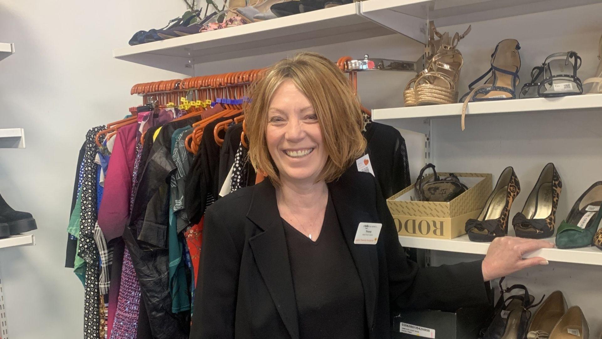 Woman with red hair standing in front of a rail of shoes and clothes