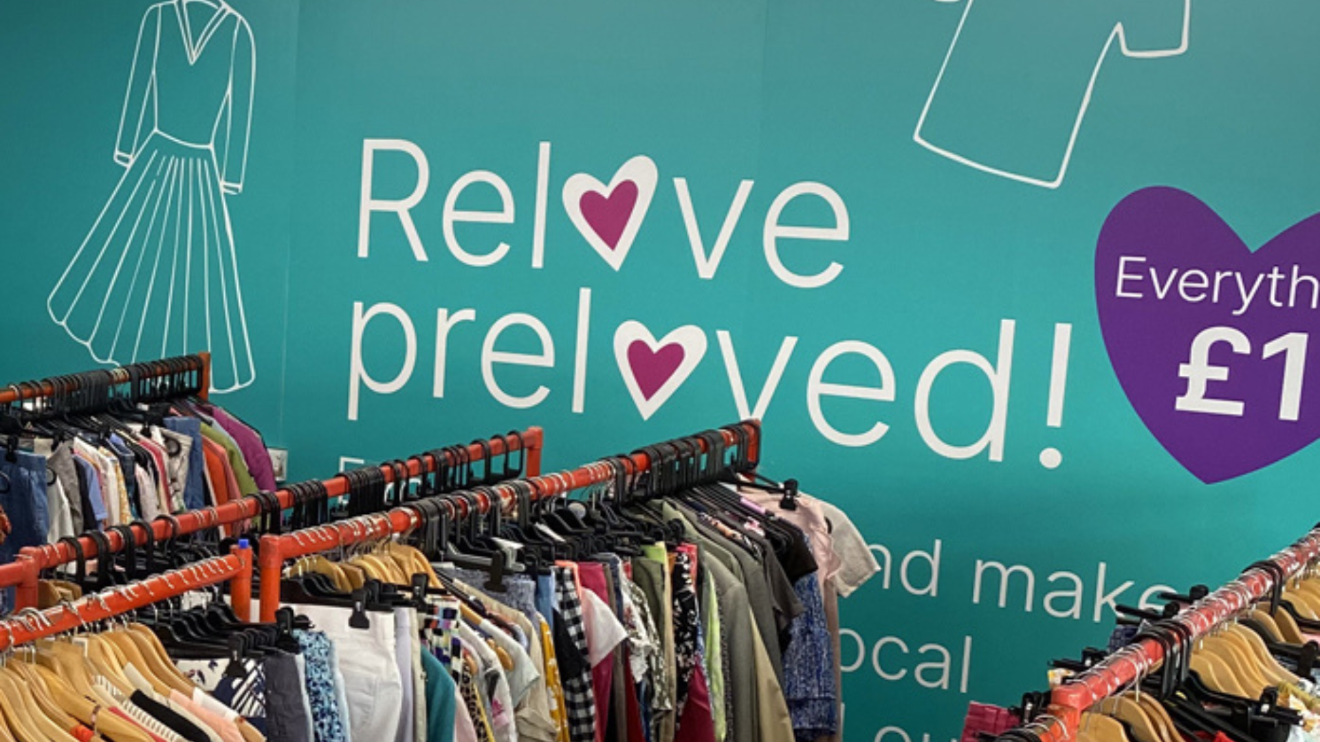 A vinyl sticker on a green wall labeled 'Reloved, reimagined'