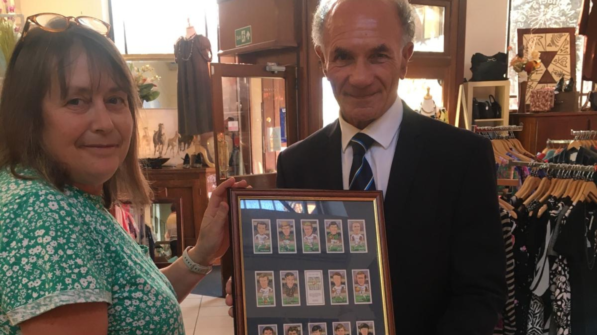 Man and woman holding up frames football cards with autograph