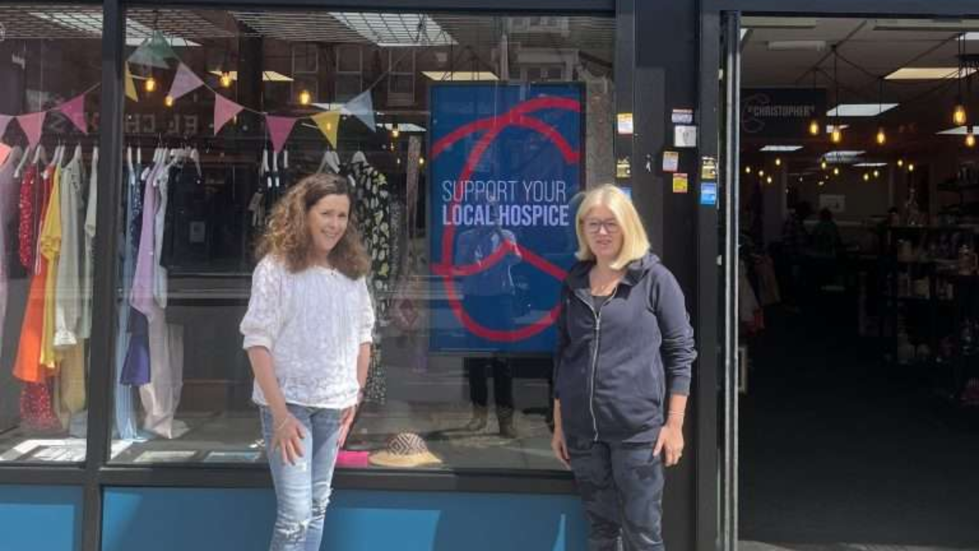 Two ladies standing outside a charity shop window