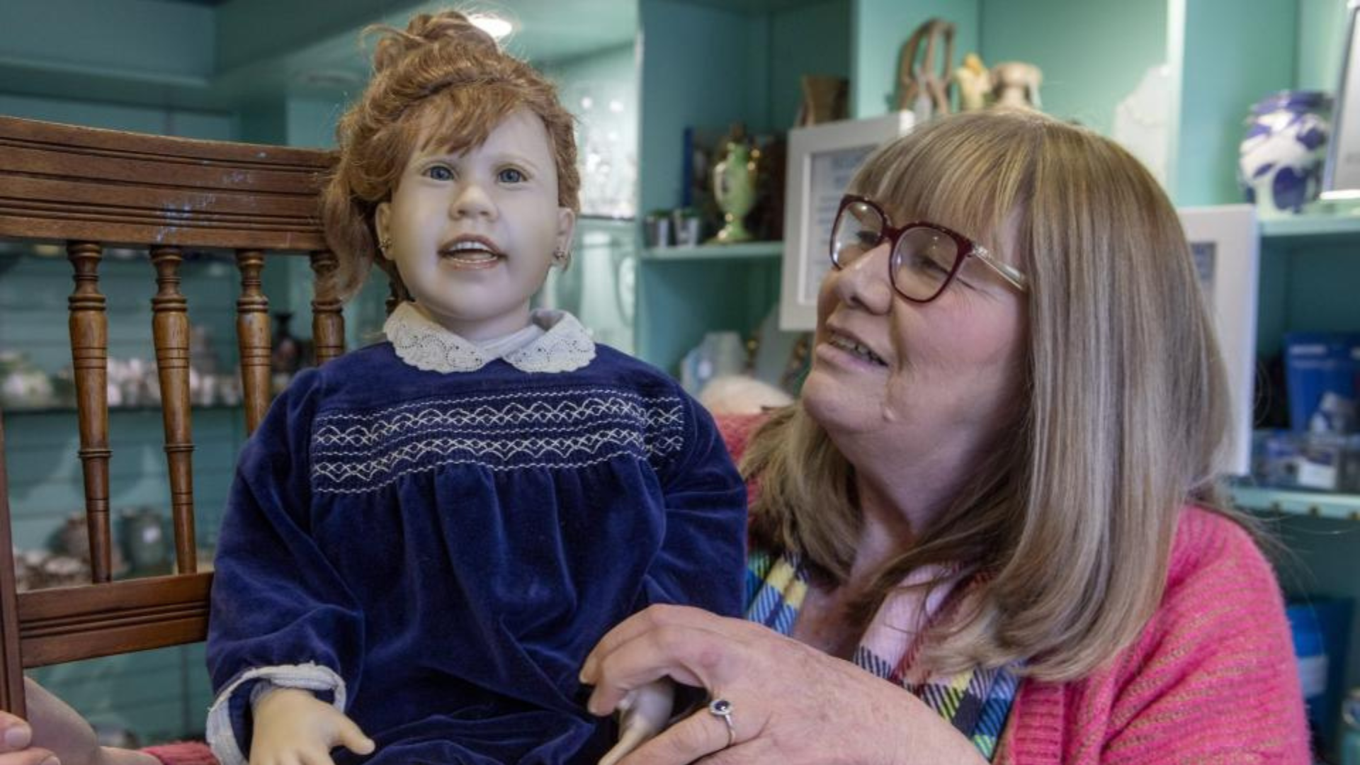 A lady with glasses holding a doll