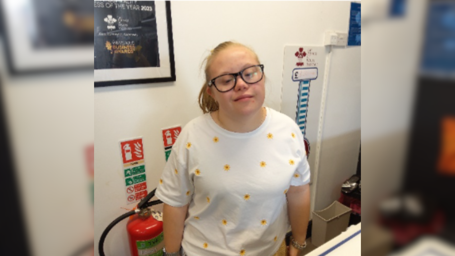 A young girl wearing glasses smiles at the camera