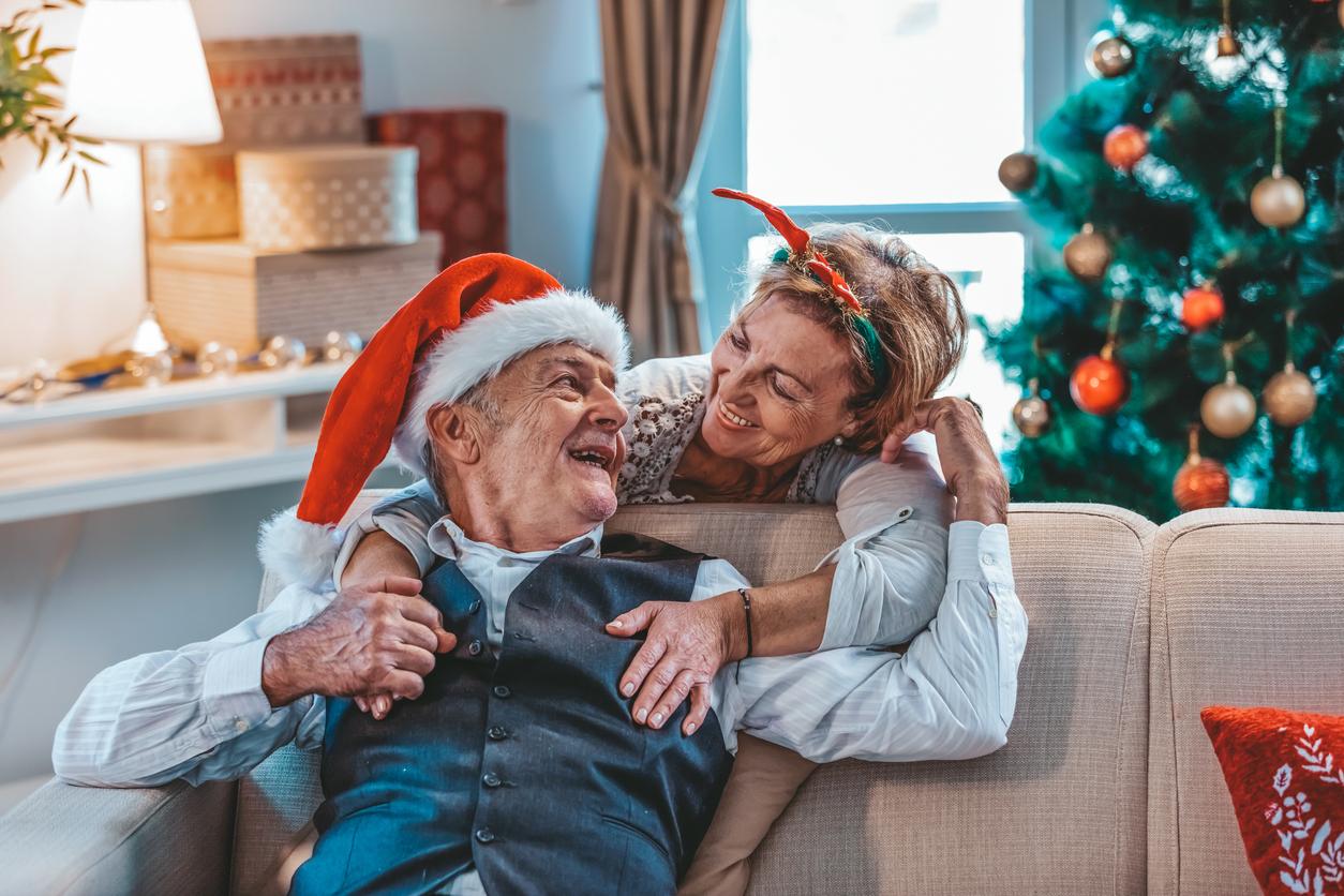 Elderly couple hugging in front of the Christmas tree