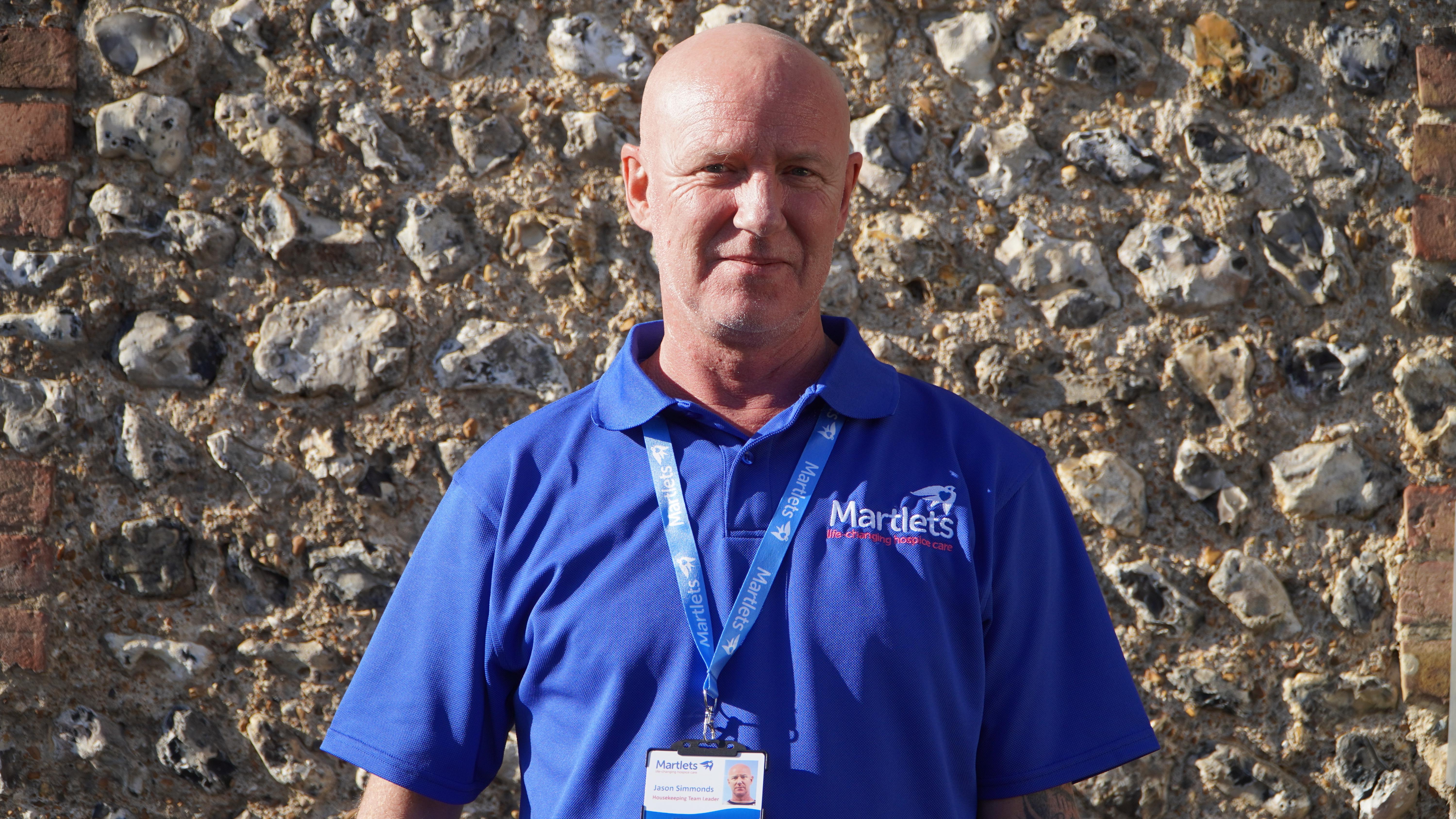 A male hospice staff member wearing a blue shirt facing the camera