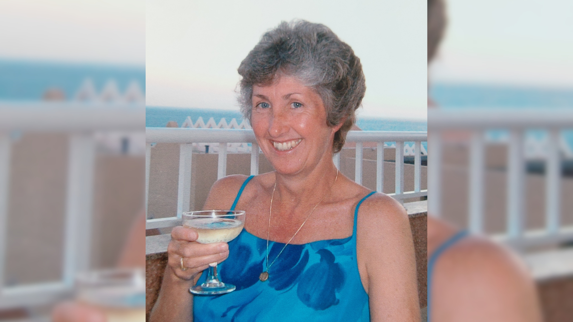 A woman wearing a blue dress holding a drink
