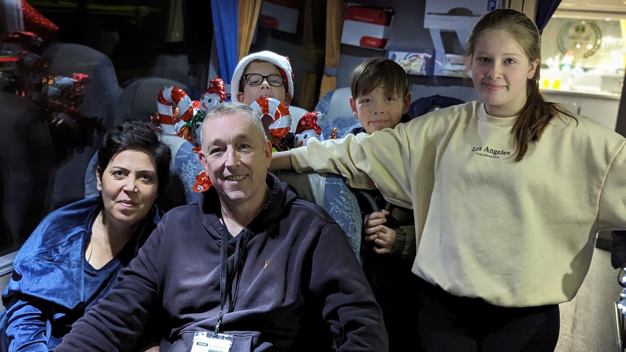A family huddled together on a bus and smiling