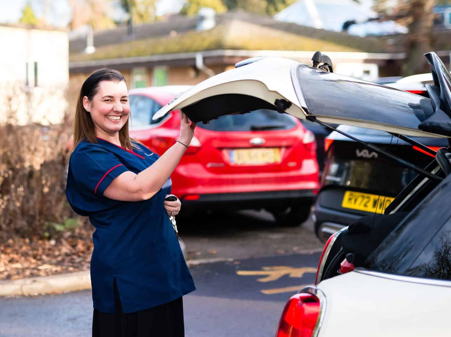 A palliative care nurse closing the boot of her car