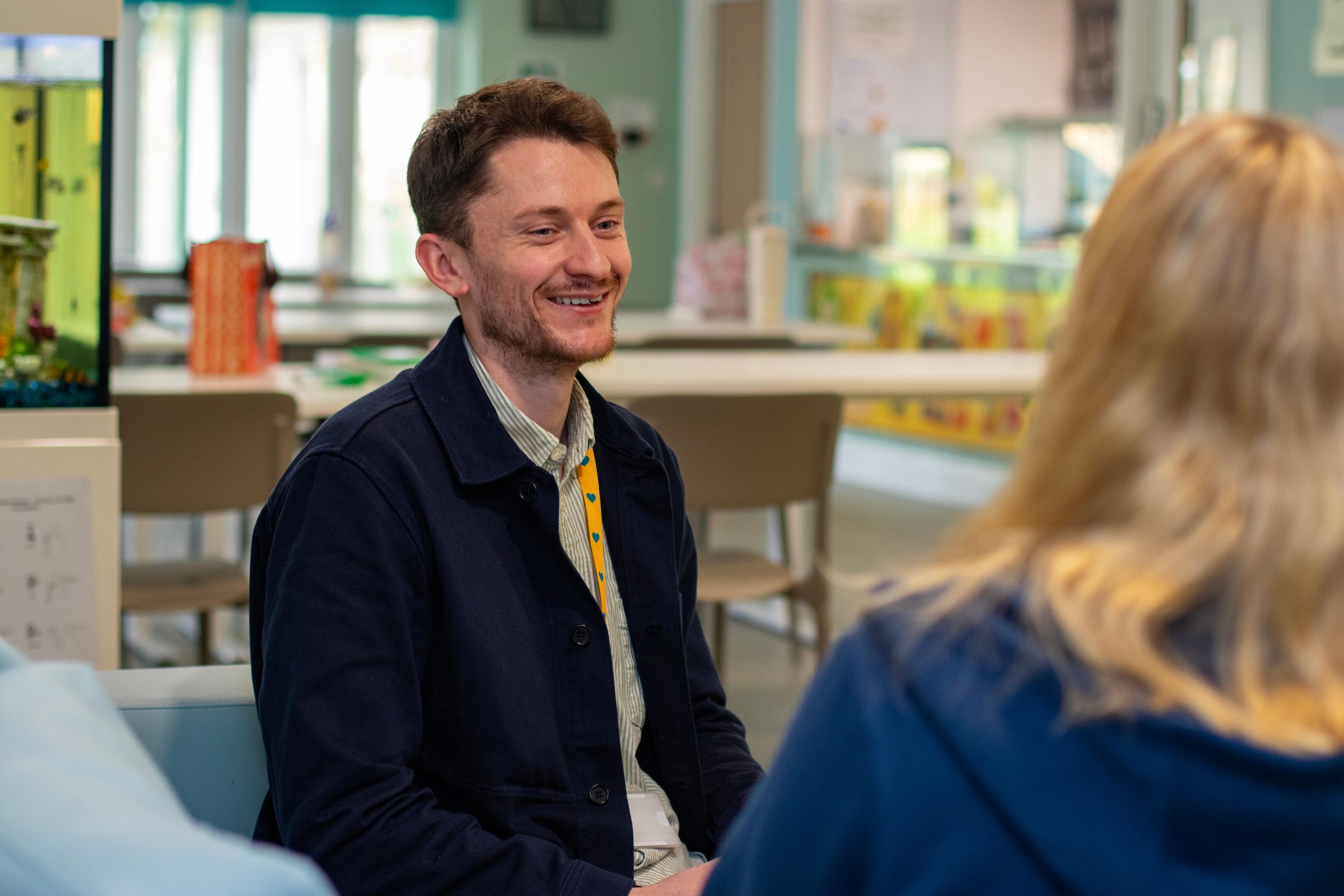 A man in a blue fleece sitting and smiling at a woman with blonde hair