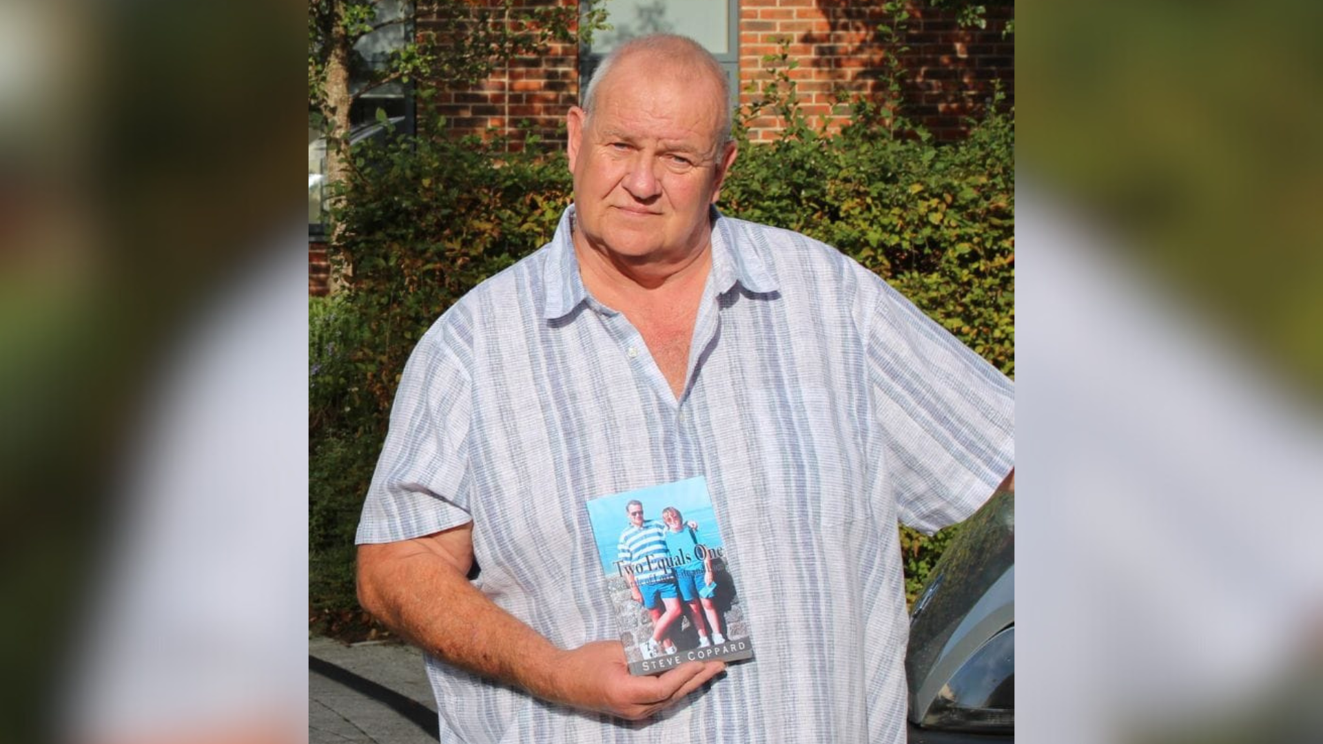 A man wearing a shirt and holding up a book