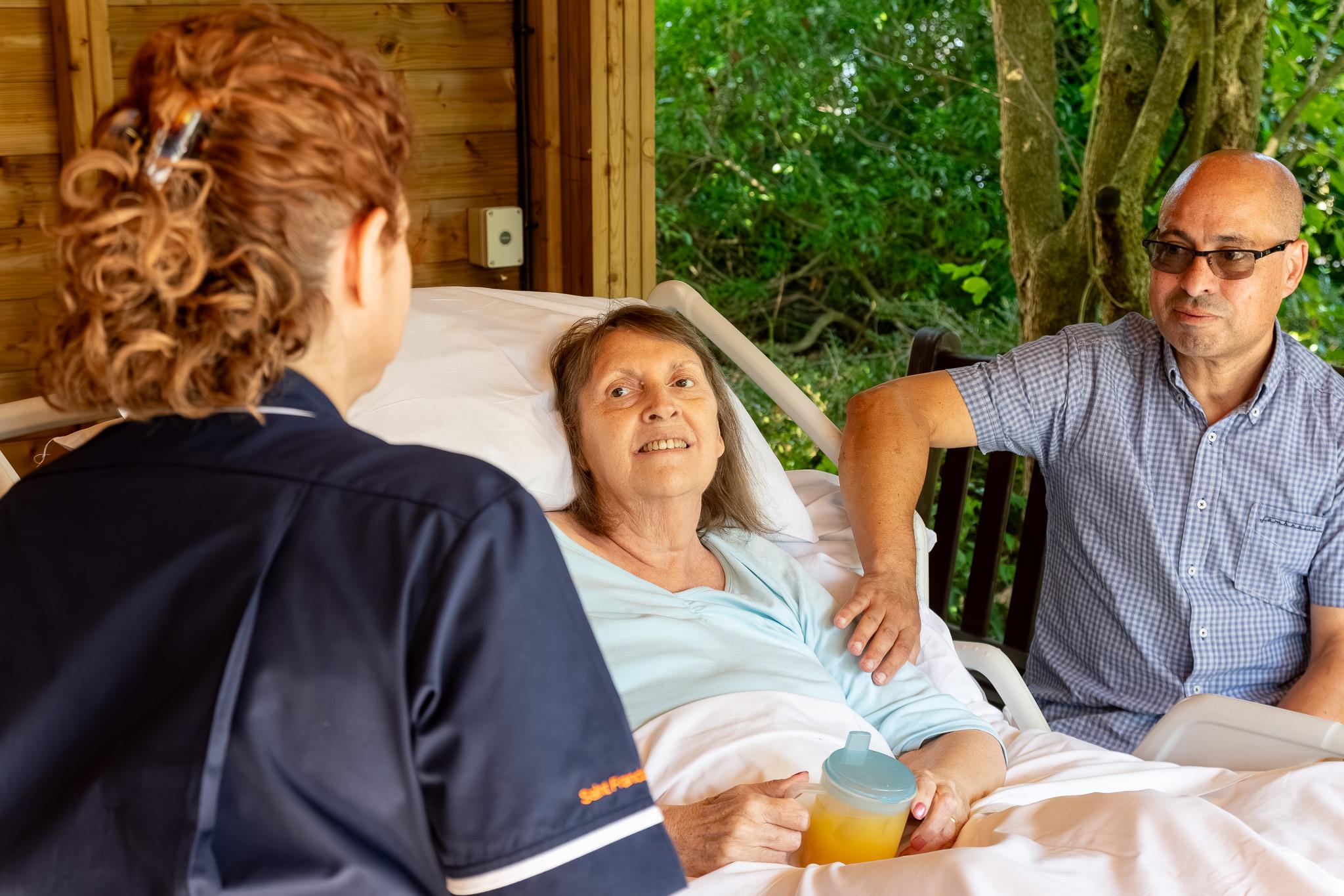 A patient in a hospital bed outside under a pergola
