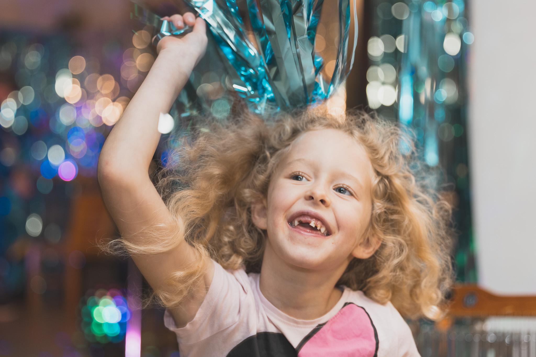 A young hospice patient dancing and holding blue tinsel