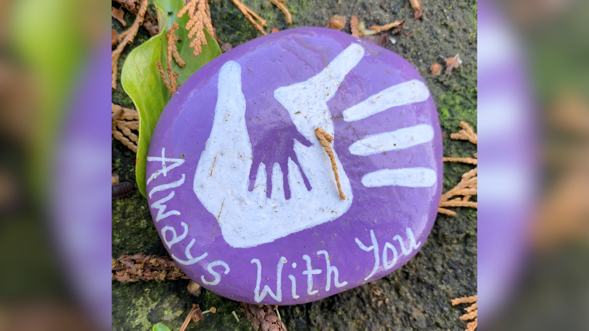 A purple stone with a white painted handprint on it