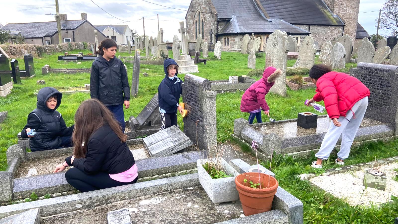 A family continues the Sul y Blodau tradition by cleaning family graves and laying flowers