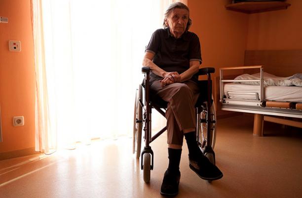 Stock photo of women in wheelchair facing away from a window that has sunlight streaming through