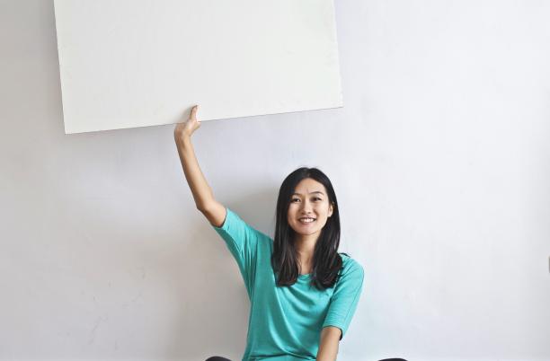 Stock photo of smiling woman holding up a blank poster