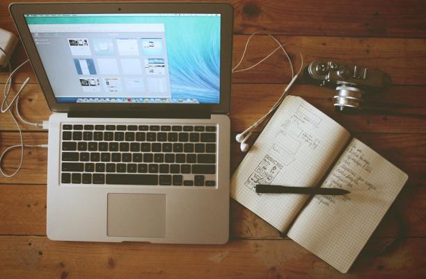 Desk with laptop, notebook and headphones