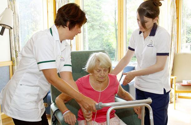 Two members of hospice staff safely helping a patient to their feet