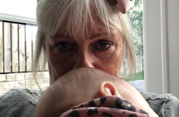 a woman with blonde hair kisses a baby's head