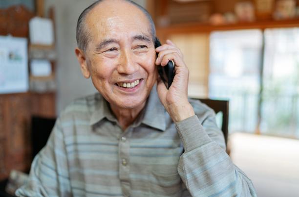 Older man is smiling as he talks on the phone
